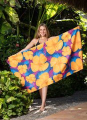 Woman holding a colorful floral Beach towel in a tropical setting