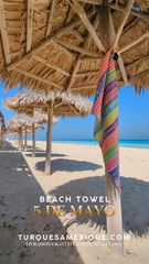 Beach scene with straw umbrellas and a colorful beach towel draped over one, with promotional text for turquesamexique.com